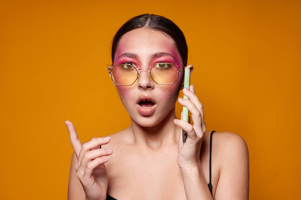 Young beautiful woman with glasses bright makeup posing black jersey talking on the phone isolated background unaltered - Φωτογραφία, εικόνα