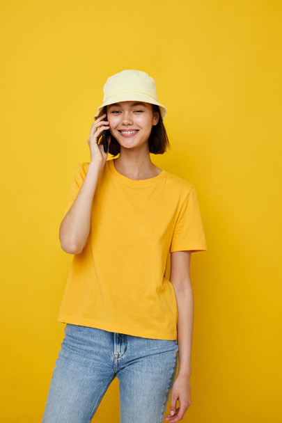 young beautiful woman in a yellow hat Youth style casual talking on the phone isolated background - Fotó, kép