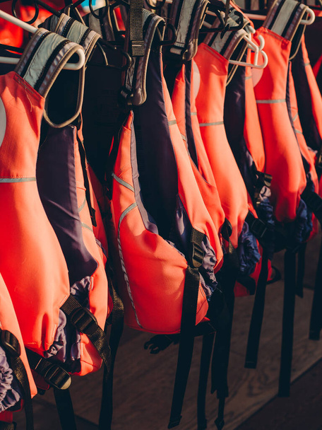 Rettungsweste auf Schiene für den Kunden, Rote Rettungsweste mit schwarzen Gürteln, Persönliches Schwimmgerät. Schwimmweste bereit für Touristen, die eine Bootsfahrt unternehmen. - Foto, Bild
