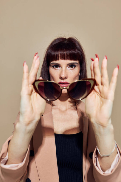 beautiful woman in sunglasses short haired suit gesturing with hands light background - Фото, зображення