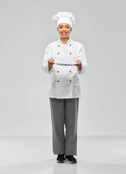 happy smiling female chef holding empty plate - Foto, afbeelding