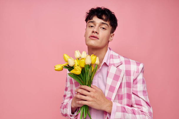 cute guy in a plaid jacket with a bouquet of flowers gift date - Foto, afbeelding