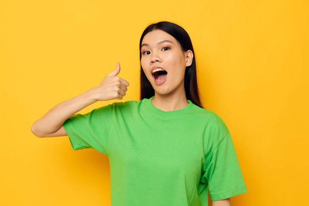 Charming young Asian woman posing in green t-shirt emotions copy-space isolated background unaltered - Fotografie, Obrázek