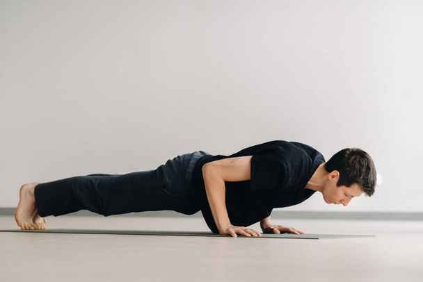A man in a black T-shirt trains lying down doing stretches in the gym. - Foto, Imagem