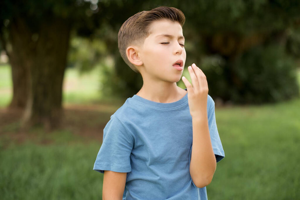  beautiful Caucasian little kid boy wearing blue T-shirt standing being tired and yawning after spending all day at work. - Fotoğraf, Görsel