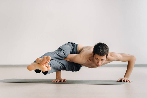 A man with a bony torso trains lying down, doing a handstand in the gym. - Foto, Imagen