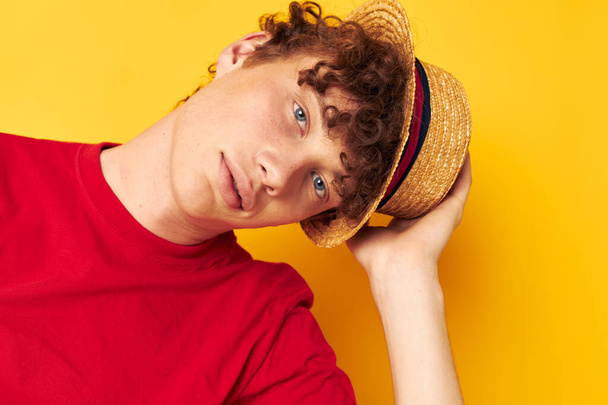 Young curly-haired man emotions red t-shirt hat studio yellow background unaltered - Photo, Image