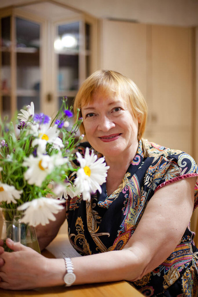 Ältere Frau mit Strauß lebender Wildblumen im Haus. - Foto, Bild