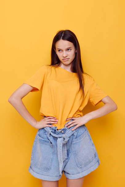 young beautiful woman fashion in yellow t-shirt denim shorts isolated background - Photo, image