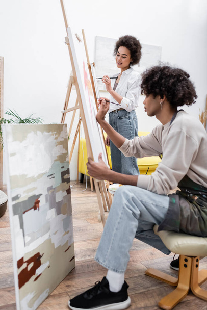 Couple afro-américain peinture sur chevalets dans le salon  - Photo, image