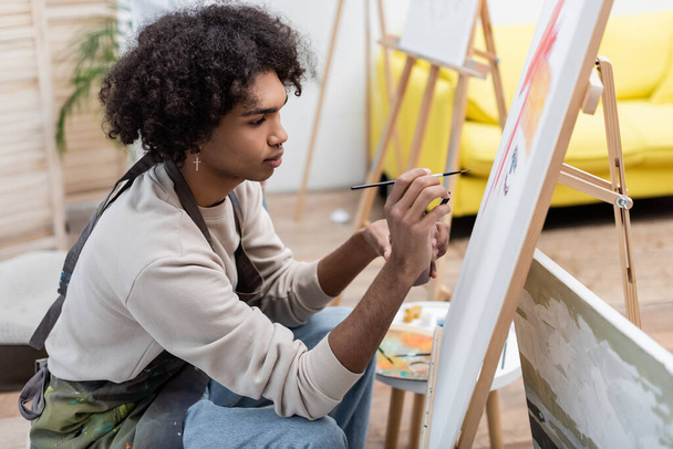 Junger afrikanisch-amerikanischer Mann malt zu Hause auf Leinwand  - Foto, Bild