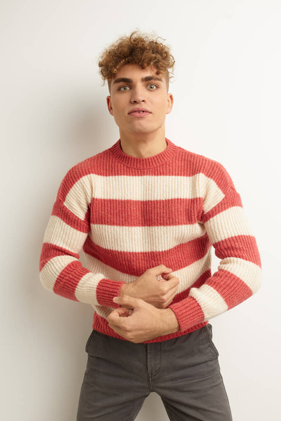 handsome young man in a striped sweater posing isolated background - Фото, зображення