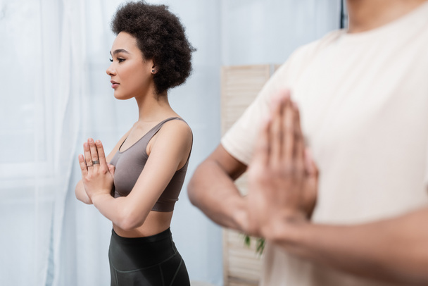 African american woman practicing yoga near blurred boyfriend at home  - Valokuva, kuva