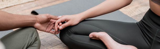 Cropped view of african american couple holding hands while practicing yoga at home, banner  - Photo, Image