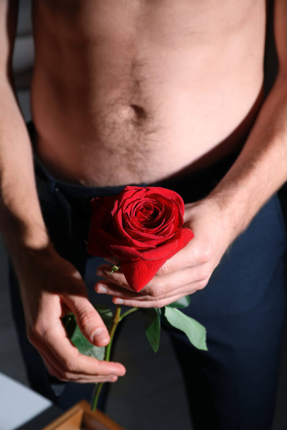 Young man holding red rose, closeup. Erotic concept - Φωτογραφία, εικόνα