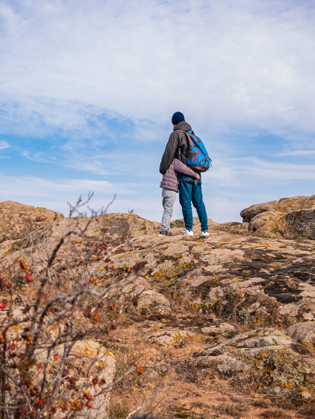Travelers father and daughter walking climbing on mountain summit enjoying aerial view blue cloudy sky back view together. Active Lifestyle tourism Family Travel Scenic landscape hiking trail Backpack - Photo, Image