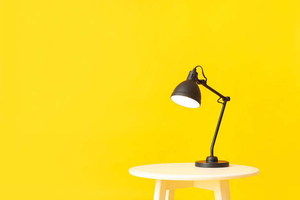 Table with stylish lamp on color background - Foto, afbeelding