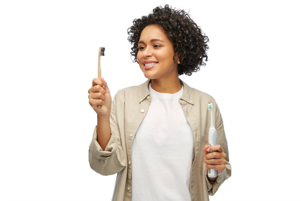 woman comparing wooden and electric toothbrushes - Photo, image