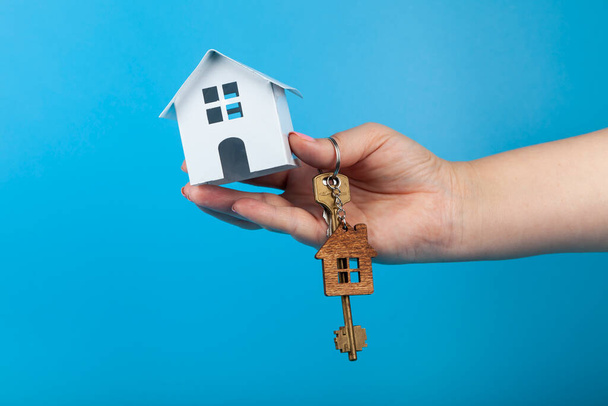 Rent apartments, Real Estate and buying a house idea.  Hand with a toy house and keys.Blue background. - Фото, зображення