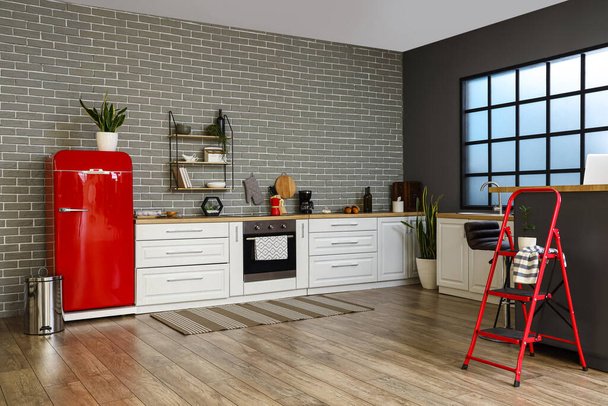 Interior de la elegante cocina con nevera roja, mostradores blancos y ventana - Foto, Imagen