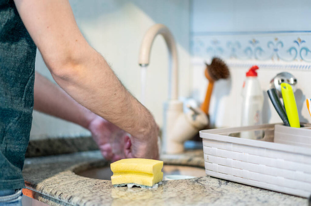 Nierozpoznawalny człowiek zmywający naczynia. Facet robi prace domowe. Koncepcja równości, feminizmu - Zdjęcie, obraz