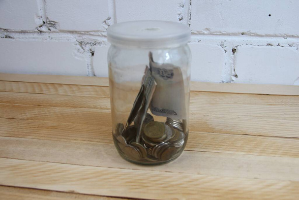 木製の背景にロシアのお金のルーブルと透明なガラス瓶 - 写真・画像