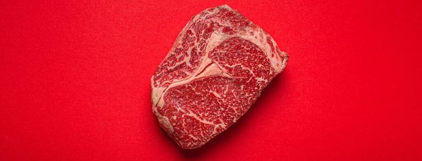 Πρώτου κρέατος βόειο κρέας προνομιακή μπριζόλα Ribeye σε καθαρό κόκκινο φόντο από πάνω, beefsteak έννοια πανό μινιμαλισμός - Φωτογραφία, εικόνα