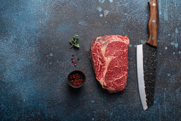 Мясо из говядины, отделанное мрамором, стейк Ribeye на деревенском обетонном столе - Фото, изображение