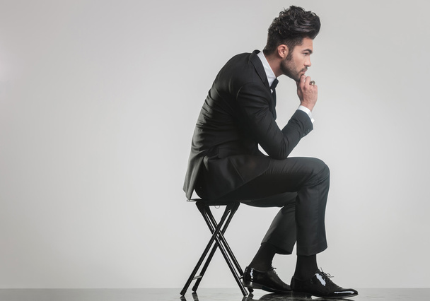 elegant young man sitting on a stool and thinking - Photo, Image