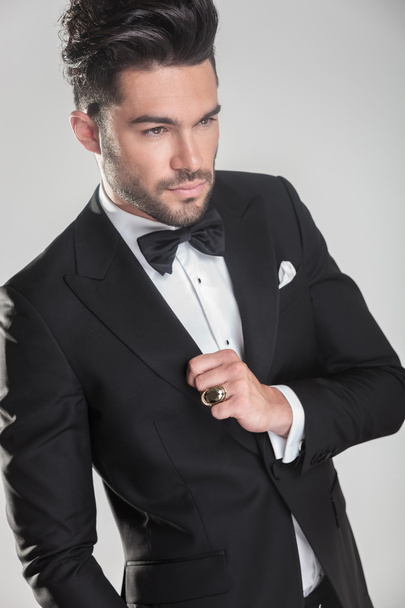 Angle view of an elegant young man ajusting his tuxedo - Photo, Image