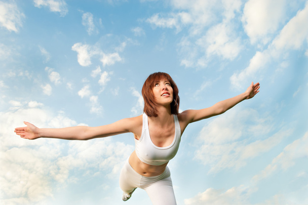 Mujer atlética balanceándose frente al cielo azul
 - Foto, imagen