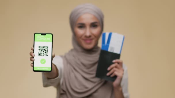 Young middle eastern woman tourist with passport and tickets showing Covid-19 vaccination certificate on smartphone - Footage, Video