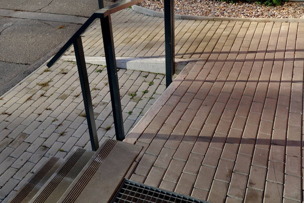 escaleras de hormigón con ranuras antideslizantes. junto a las escaleras hay una rampa para sillas de ruedas en la entrada del apartamento, casa. rejilla de metal para la limpieza de zapatos en un hueco en las baldosas - Foto, imagen