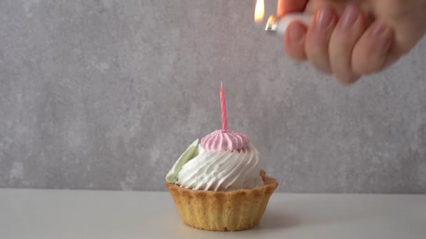 kobieta ręka zapala świeczkę na waniliowe babeczki, urodziny - Materiał filmowy, wideo