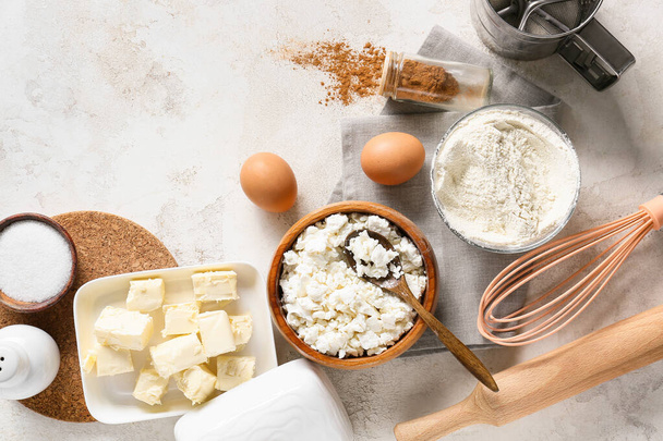 Bowl with cottage cheese and ingredients for preparing pancakes on light background - Foto, Imagen
