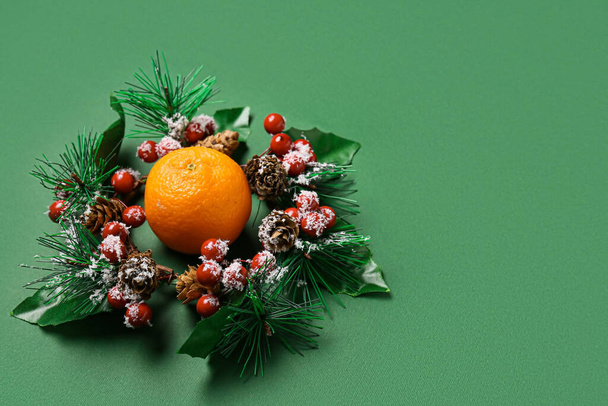 Composição com grinalda de Natal e tangerina madura sobre fundo verde - Foto, Imagem