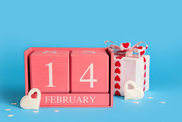 Calendar with date of Valentines Day and gift box on blue background - Photo, Image