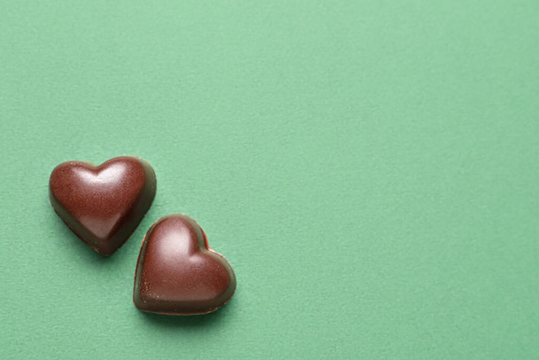 Tasty heart-shaped candies on green background - Photo, Image