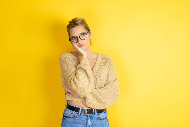 Young beautiful woman wearing casual sweater over isolated yellow background thinking looking tired and bored with crossed arms - Photo, image