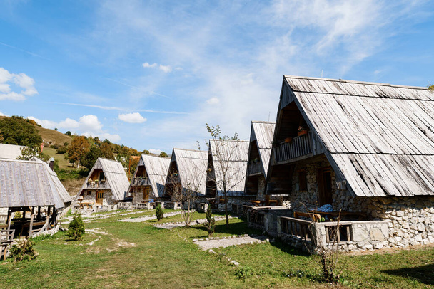 Casas de pedra triangular com telhados de madeira contra o pano de fundo das montanhas. Montenegro - Foto, Imagem