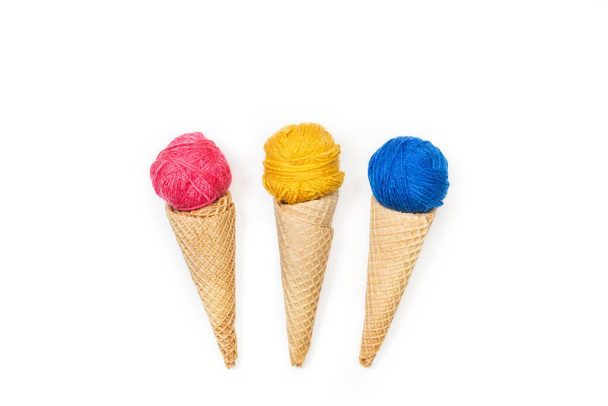 Χρωματιστές μάλλινες μπάλες σε σχήμα παγωτού κώνοι γκοφρέτας σε λευκό φόντο - Φωτογραφία, εικόνα