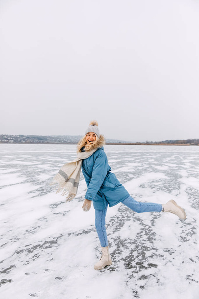 Happy young woman skating on ice on a frozen lake on a cold winter day. - Photo, image