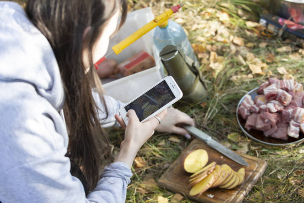 女の子はスマートフォンでバーベキューのために食べ物の写真を撮ります.Instagramのストーリーのための食品の写真. - 写真・画像