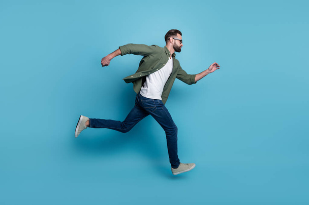 Full size profile side running fast speed traveling look copyspace casual wear isolated on blue color background - Foto, Bild
