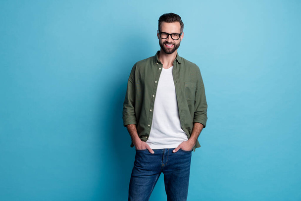 Photo of cheerful positive confident cool guy hands pockets wear green shirt isolated blue color background. - Foto, Imagem