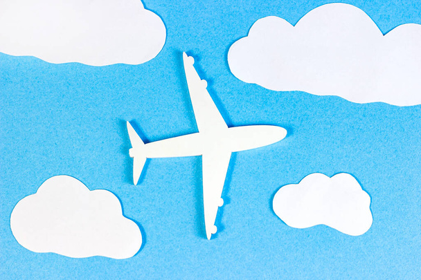 White plane model on light sky blue background with paper clouds top view flat lay. - Fotoğraf, Görsel