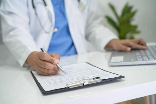 Médico escreve nota médica de saúde na área de transferência com laptop no hospital. - Foto, Imagem