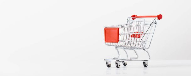 Metallic shopping cart trolley on light gray background with copy space - Фото, изображение