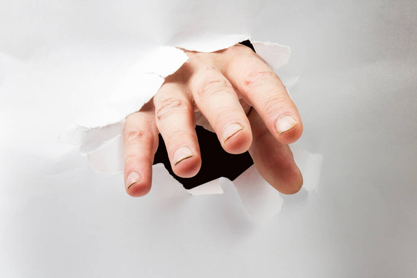 Menselijke hand doorbraak papier en reiken naar u. - Foto, afbeelding