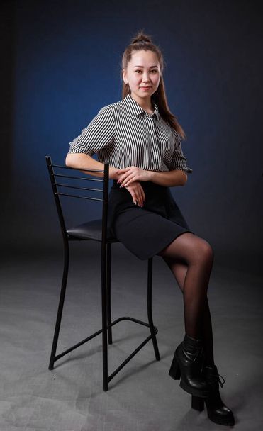 beautiful Asian business woman sitting in a high chair on a dark background - Fotó, kép
